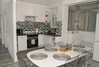 a white kitchen with a table and chairs in it at El Camino Del Mar in Valencia