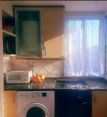 a kitchen with a washing machine and a microwave at Amplio apartamento in Puebla de Farnals