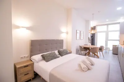 a white bedroom with two beds and a table at Favara Flats by Concept in Valencia