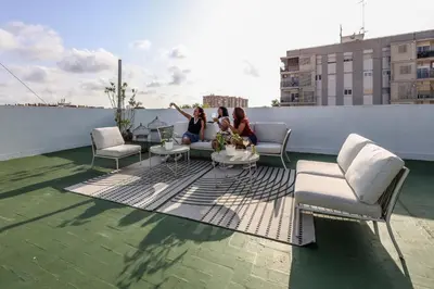 three women sitting on a rooftop patio on a building at AmazINN Valencia Cabanyal 3B in Valencia