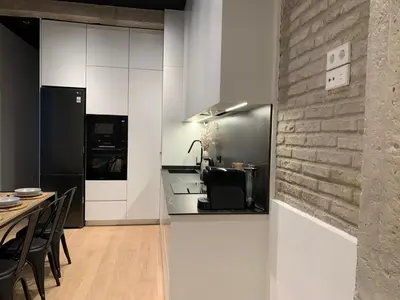 a kitchen and dining room with white cabinets and a brick wall at La Reina Beach rooms in Valencia