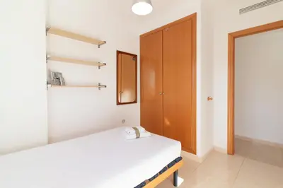 a bedroom with a bed and a wooden cabinet at Global Vacacional, Apartamento de 3 dormitorios y terraza en la playa de Canet in Canet de Berenguer