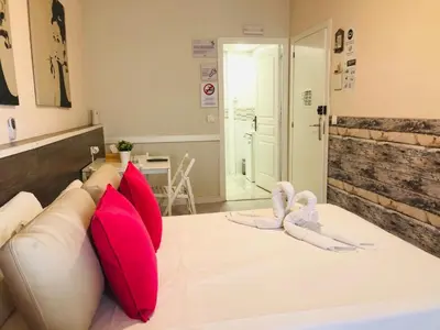 a bed with pink pillows and flip flops on it at VALENCIA SUITS YOU Centro Histórico, Establecimiento Automatizado-Fast Auto Check in&Out, Solo para Adultos-Adults only in Valencia