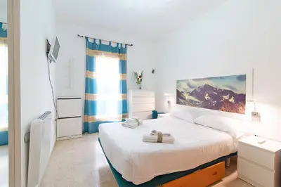 a white bedroom with a bed and a window at Global Vacacional, Práctico apartamento muy cerca del mar en Puerto Sagunto in Puerto de Sagunto