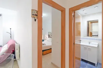 a bathroom with a mirror and a sink and a bed at Global Vacacional, Práctico apartamento muy cerca del mar en Puerto Sagunto in Puerto de Sagunto