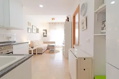 a kitchen and living room with white cabinets and a couch at Global Vacacional, Práctico apartamento en Puerto de Sagunto cerca de la playa in Puerto de Sagunto