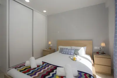 a bedroom with a large white bed with a large window at SingularStays Calderon in Valencia