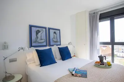 a bedroom with a large white bed with blue pillows at SingularStays Oceanografico II in Valencia