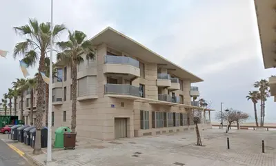 a building with palm trees in front of it at Valencia Beach Apartment - La Patacona in Valencia