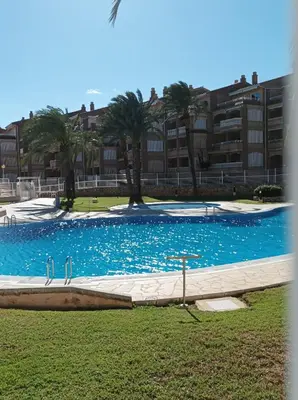 a large blue swimming pool with palm trees and a building at Almar Collection Cullera Bahía Park in Cullera