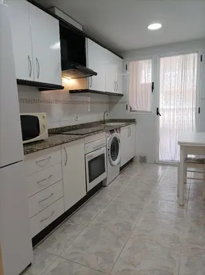 a kitchen with white cabinets and a washing machine at Almar Collection Cullera Bahía Park in Cullera