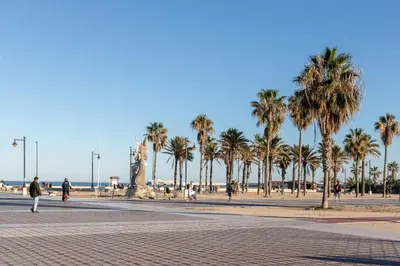 a group of people walking on a street with palm trees at Ca Celieta Beach III in Valencia