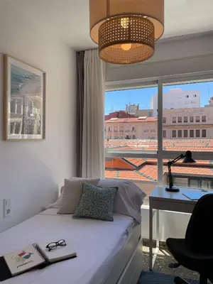 a bedroom with a bed and a desk and a window at SingularStays El Grao in Valencia