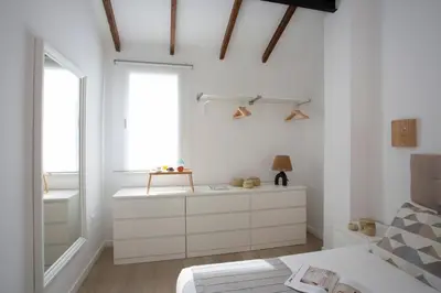 a white bedroom with a bed and a window at SingularStays Vivons in Valencia