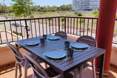 a wooden table on a balcony with plates and chairs at MAGNIFICO APARTAMENTO · PLAYA CANET DE BERENGUER in Canet de Berenguer