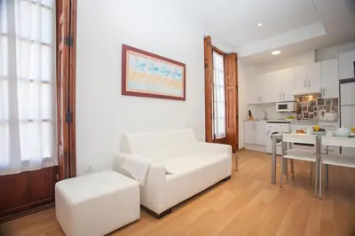 a living room with a white couch and a kitchen at Tossal in Valencia