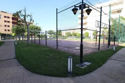 a tennis court with a fence and a tennis court at Ático con piscina en excelente urbanización by Hometels in Canet de Berenguer