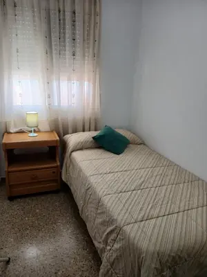 a bedroom with a bed and a nightstand and a window at Apartamento tradicional in Canet de Berenguer