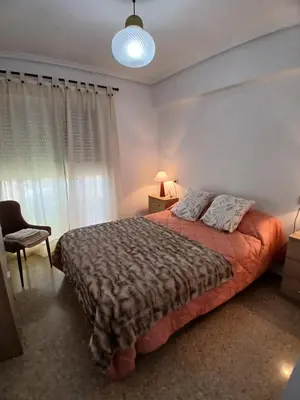 a bedroom with a bed and a lamp and a window at Apartamento tradicional in Canet de Berenguer