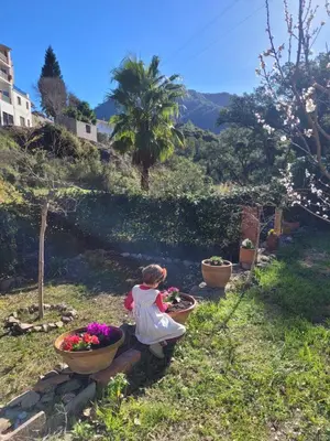 a little girl sitting in a garden with flowers at Trocito de Paraíso en la Sierra Espadán in Eslida