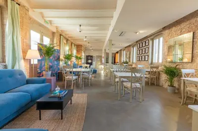 a room with tables and chairs and a blue couch at Maison Muralleta B&B in Riba-Roja De Turia