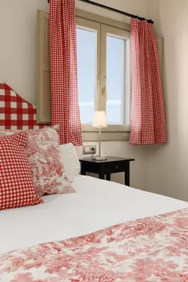 a bedroom with a bed with red curtains and a window at Maison Muralleta B&B in Riba-Roja De Turia