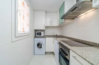 a kitchen with white cabinets and a washer and dryer at Ático Balinés con vistas al mar in Canet de Berenguer