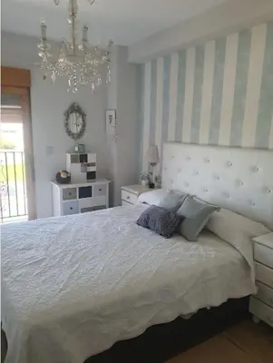 a bedroom with a large bed and a chandelier at Apartamento primerísima línea in Port Saplaya