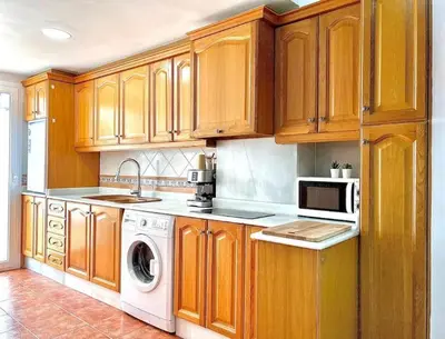 a kitchen with wooden cabinets and a washer and dryer at Apartamento con Terraza cerca de la Estación del Nord in Valencia