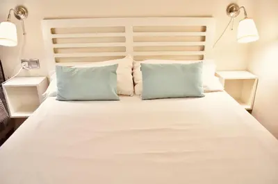 a bedroom with a white bed with two blue pillows at Estudio con encanto en el casco antiguo de Valencia in Valencia