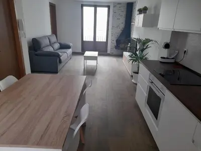 a kitchen and living room with a table and a couch at L'Amagatall in Ahín