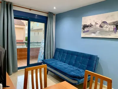 a blue couch in a living room with a table and chairs at Experience Valencia Bnb - Rincon del Mar - Apartamento Maravilloso a Canet Playa 100 mt in Canet de Berenguer