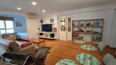 a living room with a table and a living room with a couch at Precioso apartamento a 7 minutos en tren al centro de Valencia in Benetúser