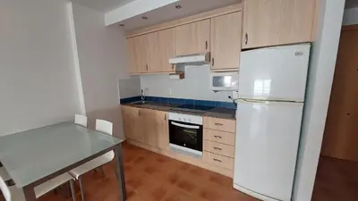 a kitchen with a white refrigerator and a table at Ático dúplex con vistas in Canet de Berenguer