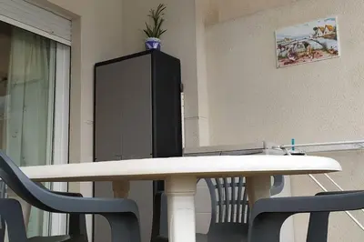 a white table with chairs and a black cabinet at Acogedor apartamento en la playa de Canet in Canet de Berenguer