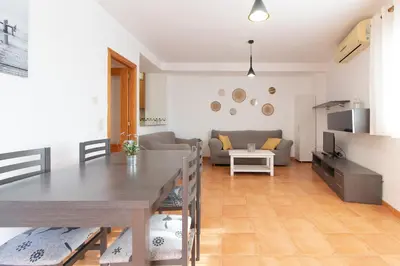 a living room with a table and a couch at Global Vacacional, Práctico apartamento con piscina en la playa de Canet in Canet de Berenguer