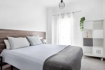 a white bedroom with a large bed and a window at Bombonera 2 Jacuzzi in Catadau