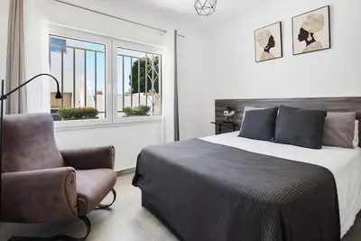 a bedroom with a bed and a chair and a window at Bombonera 2 Jacuzzi in Catadau
