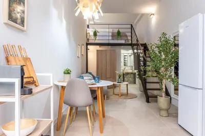 a living room with a table and chairs and a spiral staircase at Lore Loft Valencia in Valencia