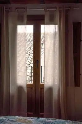 a bedroom with two windows with white curtains and a bed at Casa Rural Ana Maria Ain in Ahín