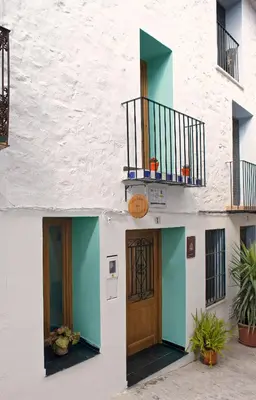 a white building with two doors and a balcony at Casa Rural Ana Maria Ain in Ahín