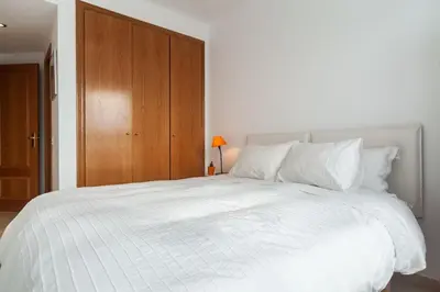 a bedroom with a large white bed with a wooden closet at Valencia las Artes y Ciencias + Garaje + Netflix in Valencia