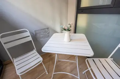 a white table and a chair and a vase with flowers at FLORIT FLATS - The Joaquin Sorolla Station Apartments in Valencia