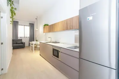 a kitchen with a refrigerator and a table in a room at GuestReady - Valencia's Vibrant Malvarrosa in Valencia