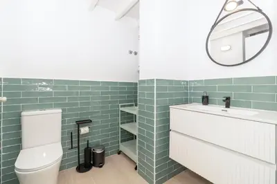 a bathroom with a white toilet and green tiles at GuestReady - Valencia's Vibrant Malvarrosa in Valencia