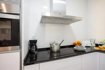 a white kitchen with a stove top oven next to a microwave at SingularStays Roteros in Valencia