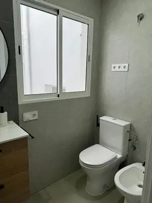 a bathroom with a toilet and a sink and a window at UIM Mediterraneo ATICO Cendoya Wifi in Puerto de Sagunto