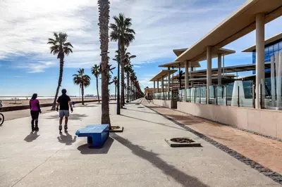 a man and woman walking down a sidewalk near the beach at Valencia Flat Rental Patacona Beach in Valencia