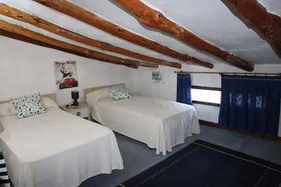 two beds in a room with blue curtains at Casa de pueblo en Calles in Calles
