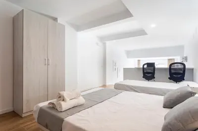 a white bedroom with two beds and two black chairs at SOROLLA APARTMENTS CENTRAL Station in Valencia